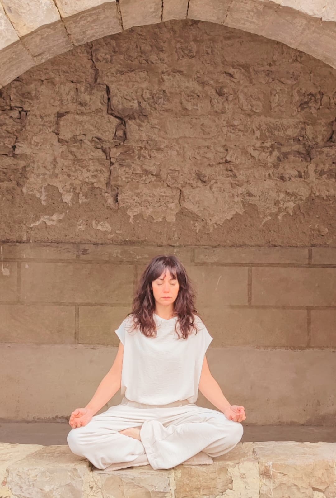 Fotografía de Susana meditando bajo un arco
