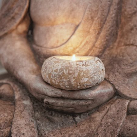 Estatua de Buda con vela entre las manos